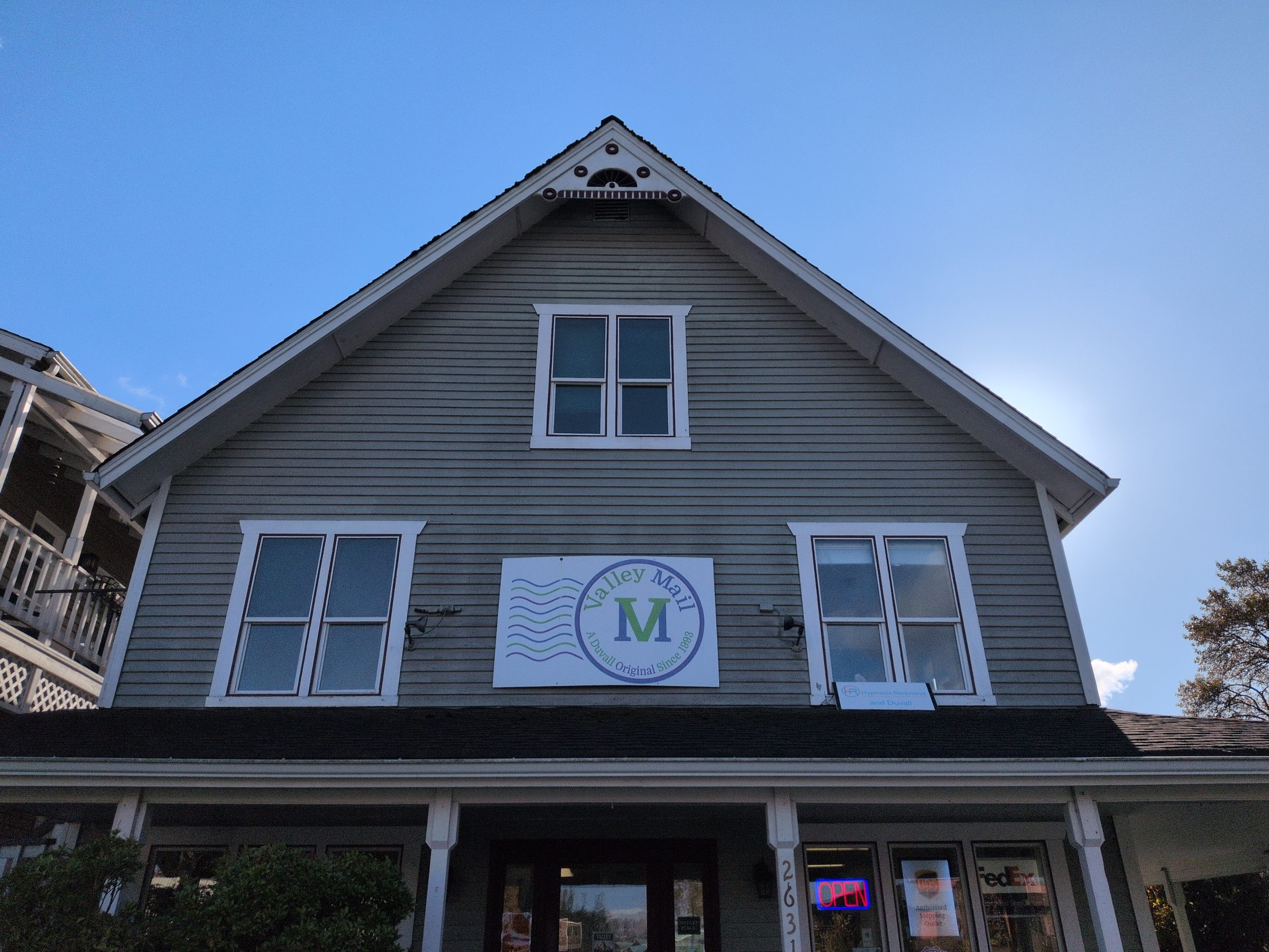 Valley Mail’s building, with the postage-stamp sign on the gray siding and the Open sign in the window